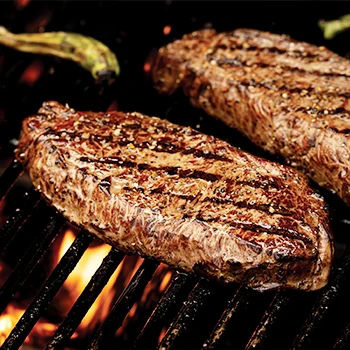 Two pieces of steak being cooked with indirect heat