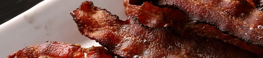 A close up shot of smoked bacon or pancetta on a white plate