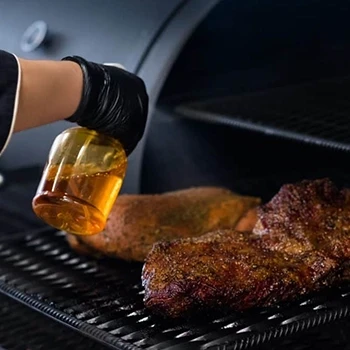 A man wearing black gloves spritzing brisket