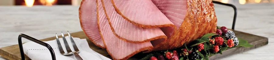 A large sliced ham on a wooden board perfect for large crowds