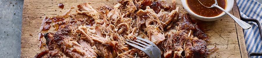 A top view of pulled pork meat on a wooden board