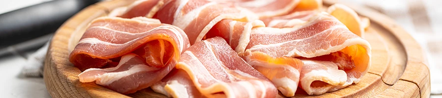 Uncooked bacon on a wooden board ready for storing in the fridge