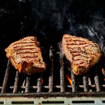 Two pieces of New York strip steak being grilled