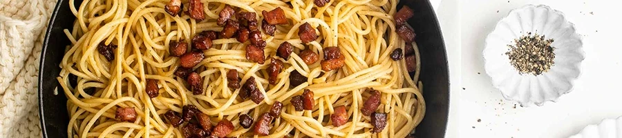 A top view of pasta with pancetta cubes on top