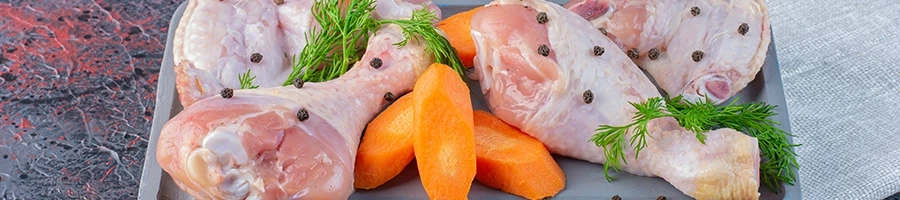 Raw chicken meat and carrots on a tray