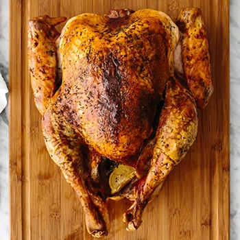 A top view of roasted turkey resting on a wooden board