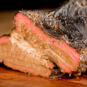 A close up shot of a juicy brisket resting on a wooden board