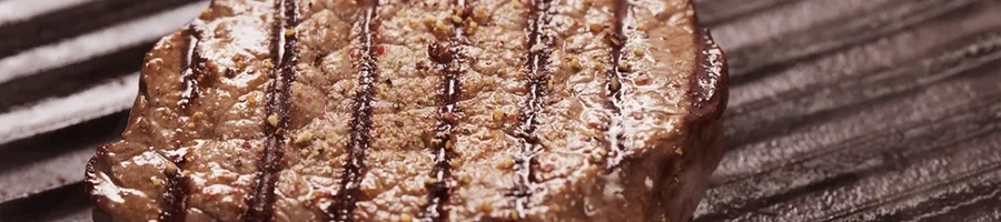 A close up shot of a steak being cooked on a griddle