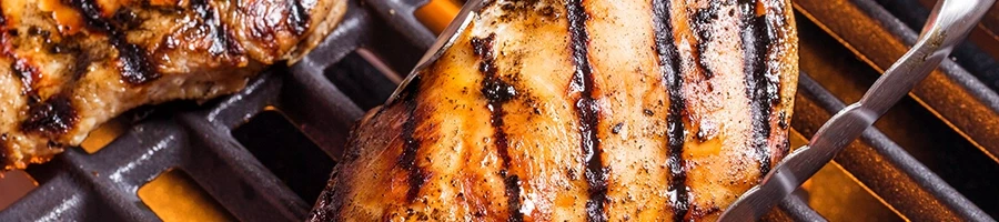 A close up shot of chicken breasts being cooked on a gas grill