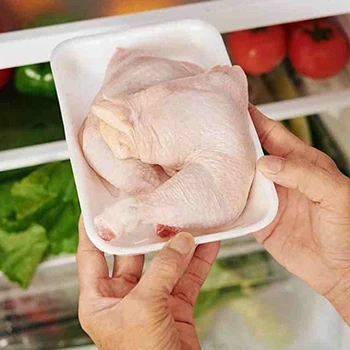 A woman storing raw chicken meat in the fridge