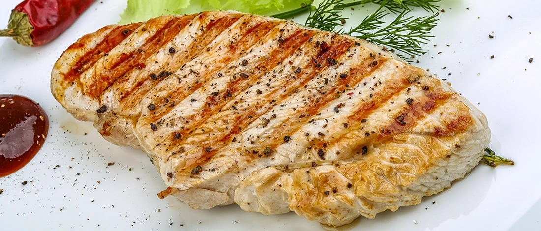 A grilled chicken breast on a white plate