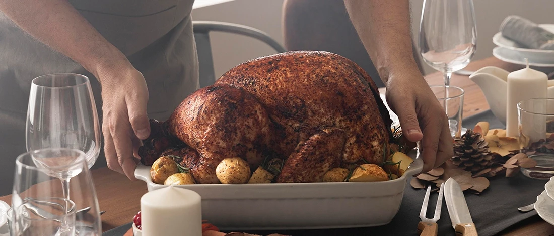 A person holding a whole turkey to reheat it