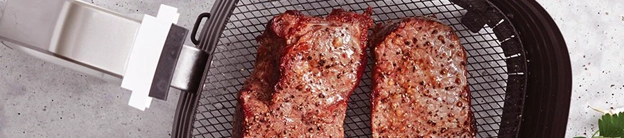 A top view of steaks placed on an air fryer to reheat