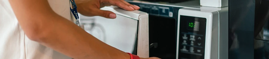 A woman using a microwave to reheat a steak