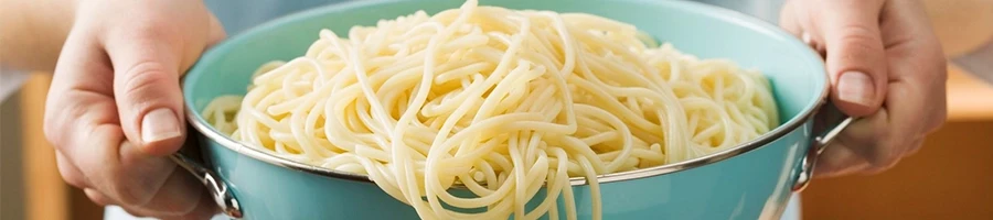 A woman holding a pot full of spaghetti noodles