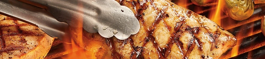 A close up shot of chicken breasts being grilled on high flames