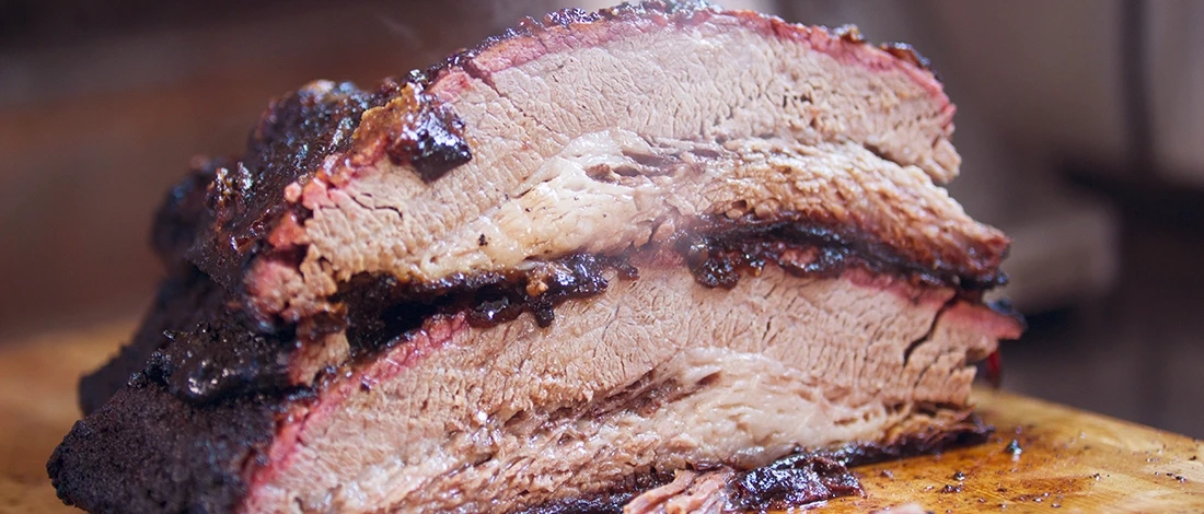 A close up shot of Texas style smoked beef brisket on a wooden board