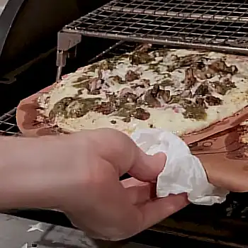 a man cooking pizza on a pellet grill
