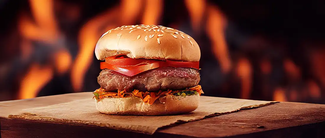 hamburger on a wooden board with flames in the background