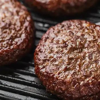 cooked burger patties on a black cooking pan