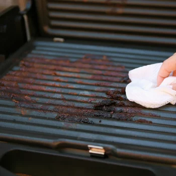 Person cleaning a grill with a cloth