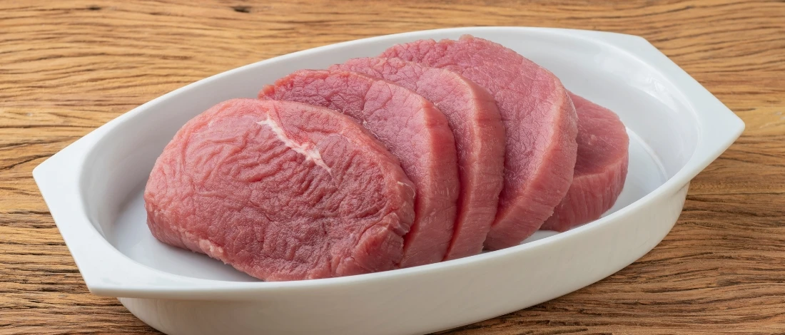 A raw eye of round steak in a white plate