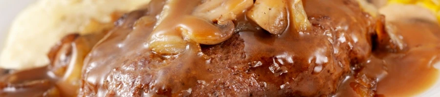 A close up shot of Salisbury steak with gravy and mushrooms