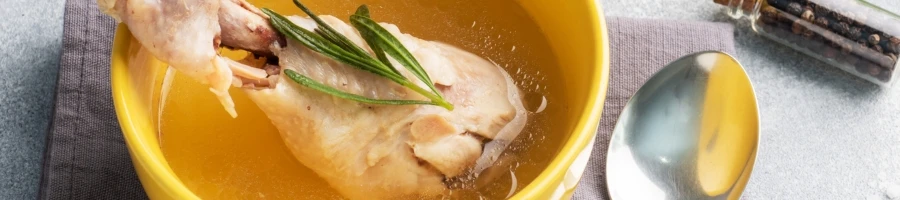 A bowl of turkey stock with a spoon on the side