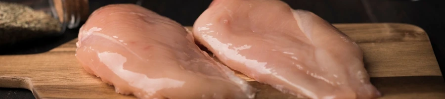 Raw chicken breasts on a wooden board