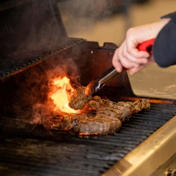 A person grilling a delicious steak