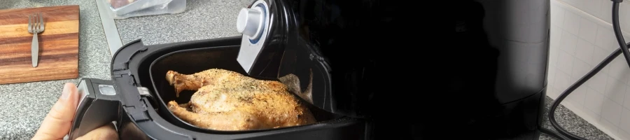 A person using an air fryer to cook chicken