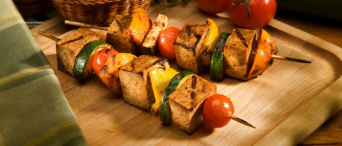 A grilled tofu skewers on a wood plate