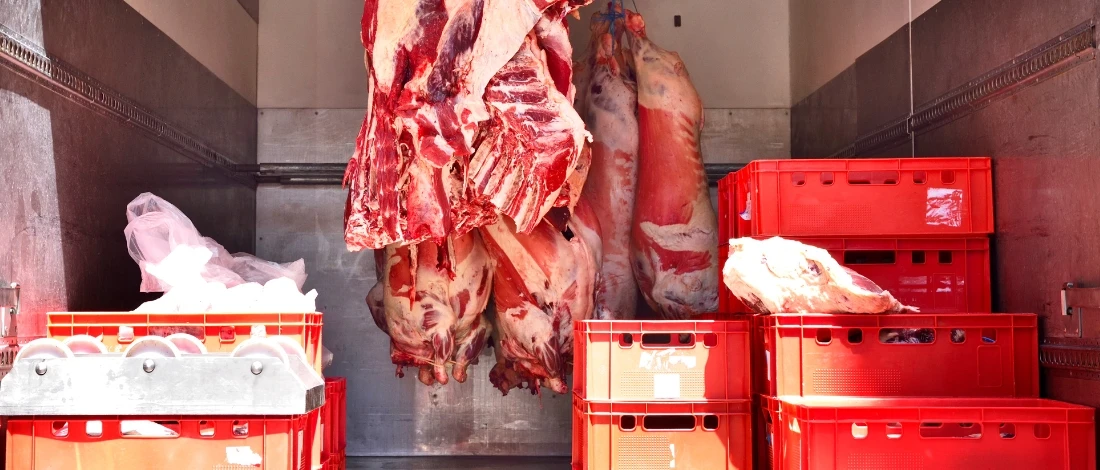 The meats are hanging inside a delivery truck