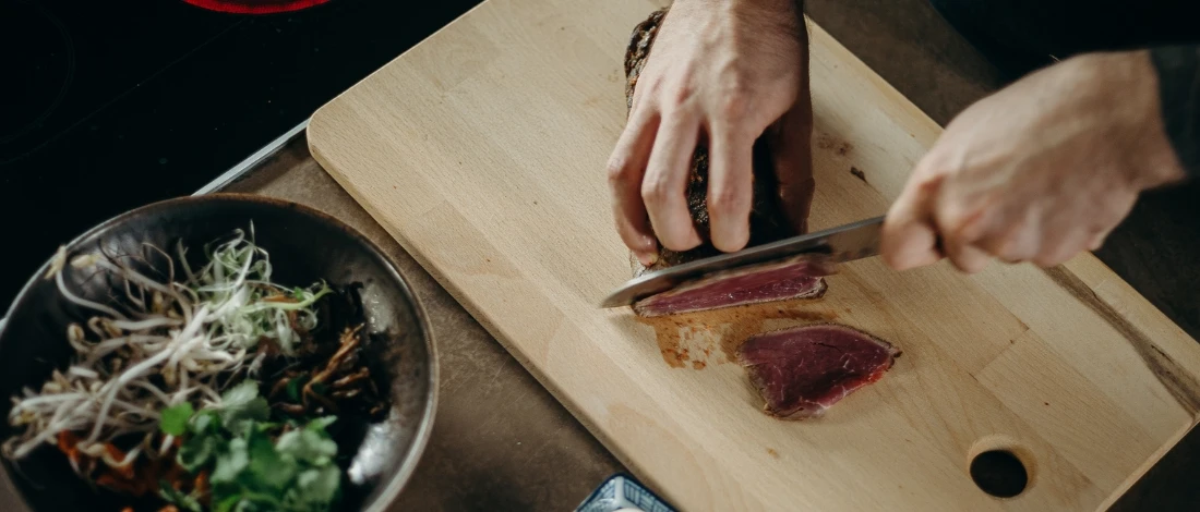 A person slicing the meat on a cutting board