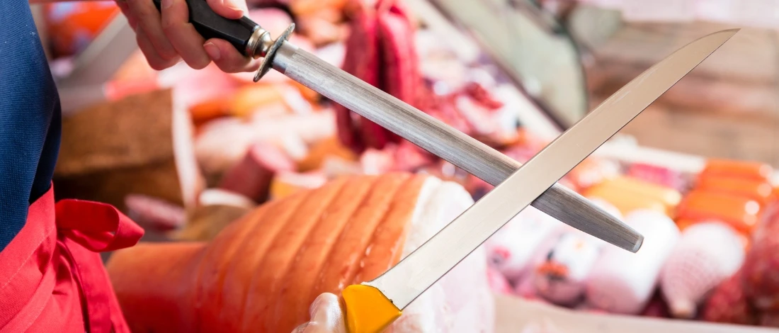 A person sharpening the knife for meat