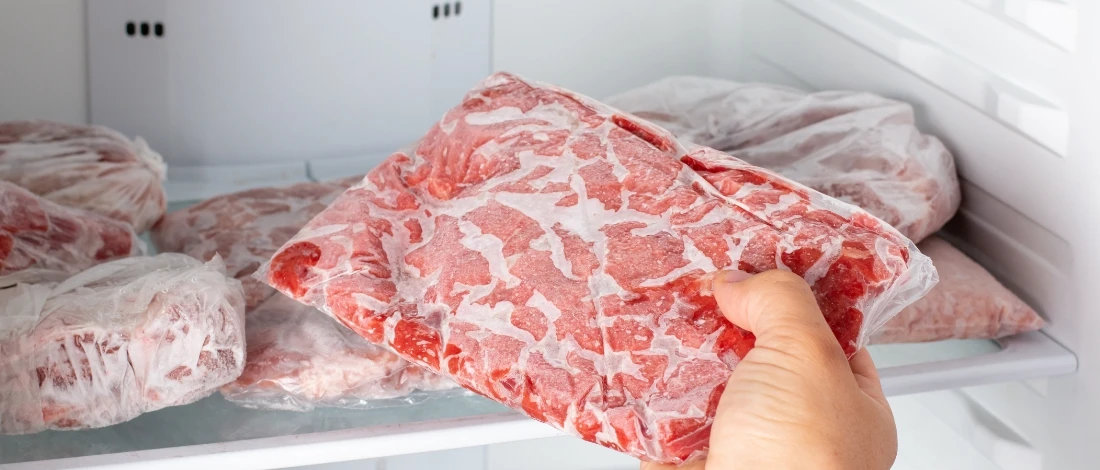 A person placing the meat in the freezer