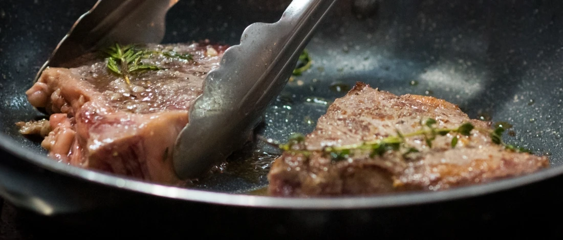 The steak cooking in a pan without a thermometer