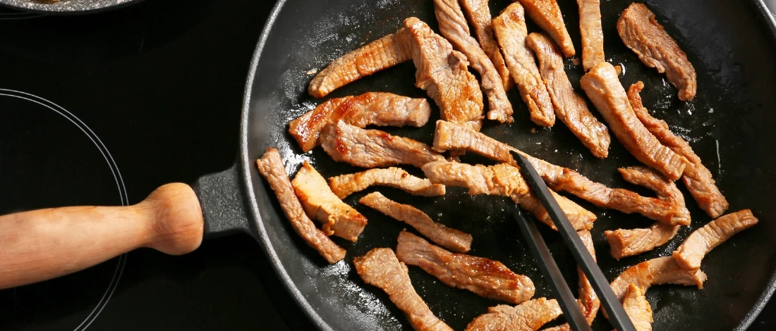 The meat cooking in a pan until it turns brown