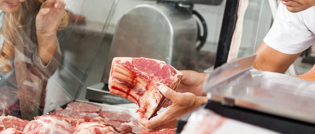A person choosing meat in a grocery