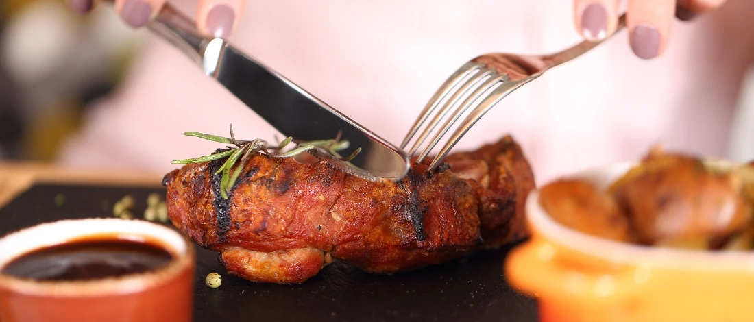 A person eating a piece of cooked meat