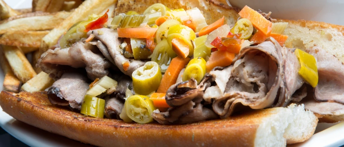 A beef sandwich filled with beef and veggies