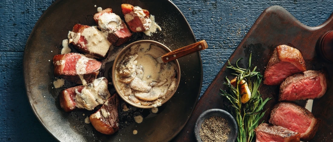 A top view of slices steak with white sauce.