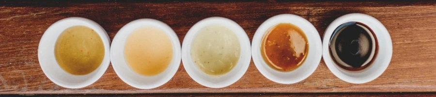 A lined bowls with different condiment and oils