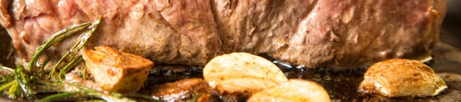 A close up shot of cooked meat with garlic and butter