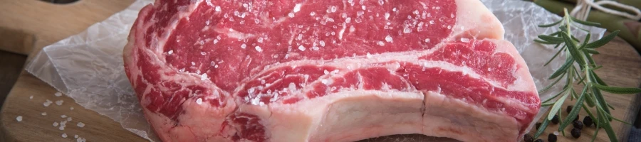 A Ribeye meat on a cutting board with salt on top