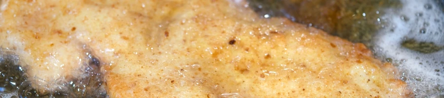 A breaded steak frying in oil