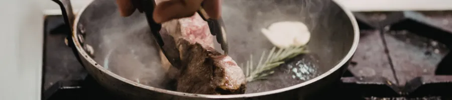 A person showing how to properly cook a deer steak